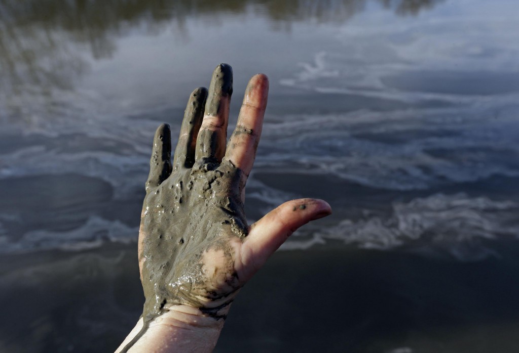 Amy Adams, North Carolina campaign coordinator with Appalachian Voices, shows her hand covered with wet coal ash from the Dan River in 2014. Photo by Gerry Broome