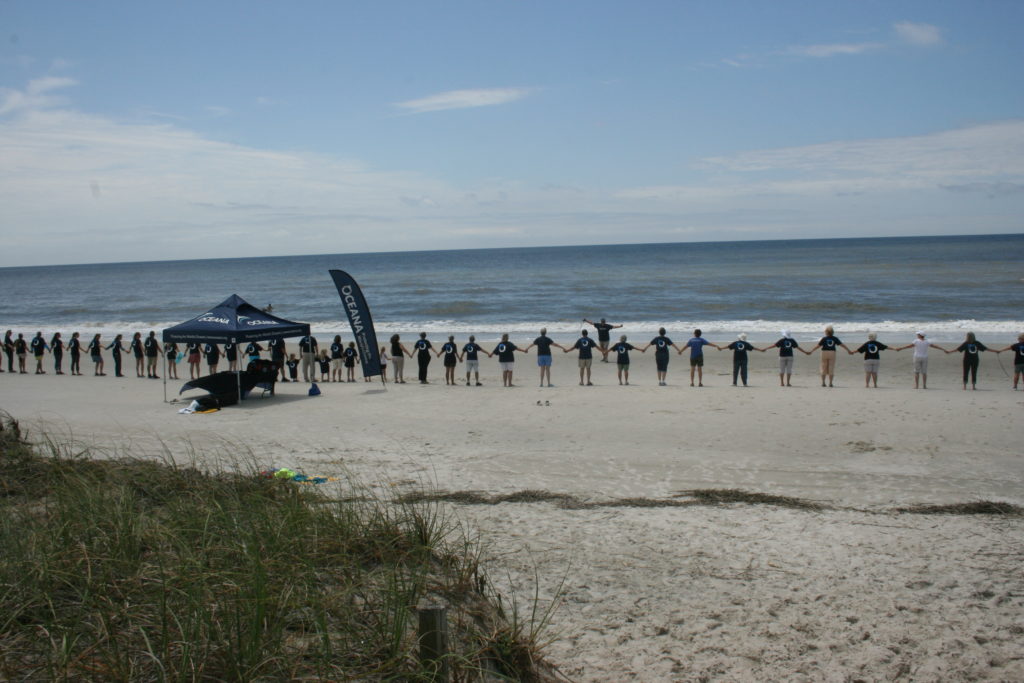 Oceana field organizer Randy Sturgill gestures to participants in the 2016 Hands Across the Sand event in Oak Island, NC as part of a nationwide protest against offshore drilling and seismic airgun blasting. (Photo: Oceana)